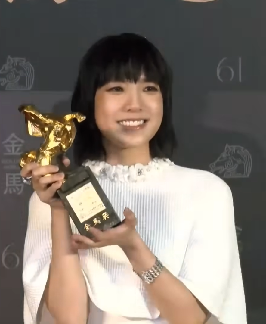 Michelle Williams holding an award trophy at a red carpet event
